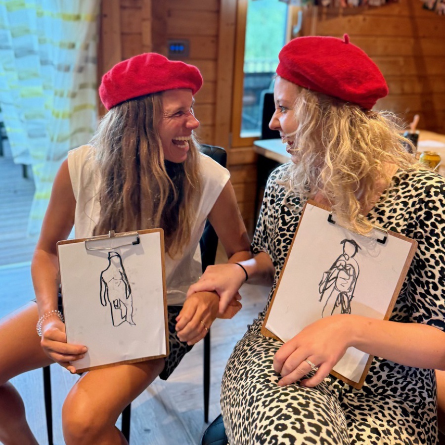 Group photo of happy hen party guests holding their completed nude life drawings after the session.