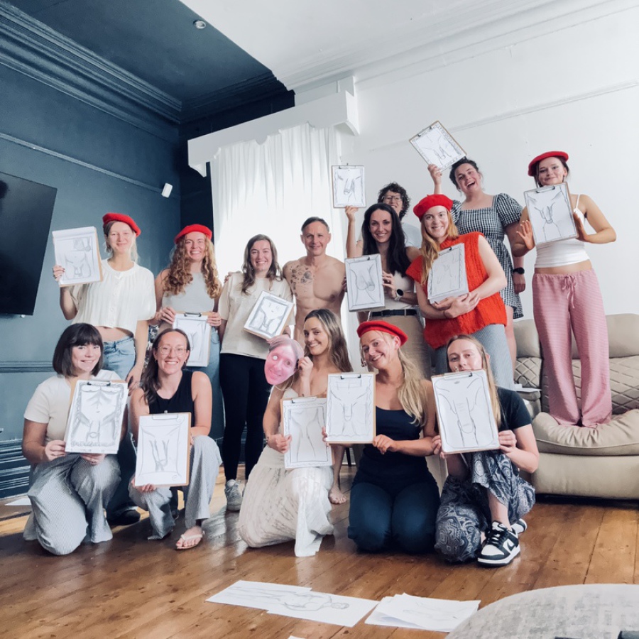Two women smiling while showing off their life drawing sketches at a hen party event.