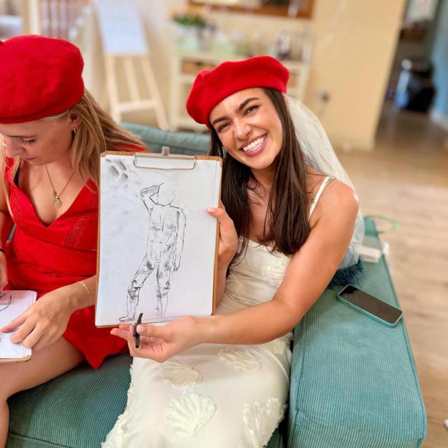 Trio of guests posing with nude life drawings at hen party art session.