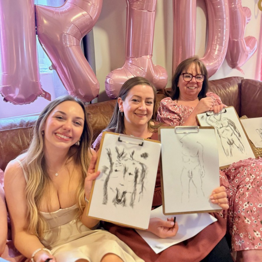 Bride and friend holding nude life drawings after mobile hen party life drawing session.