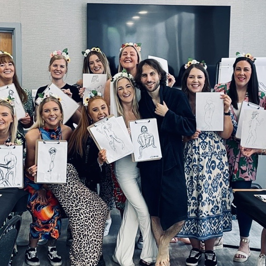 Bride and friend holding nude life drawings after mobile hen party life drawing session.
