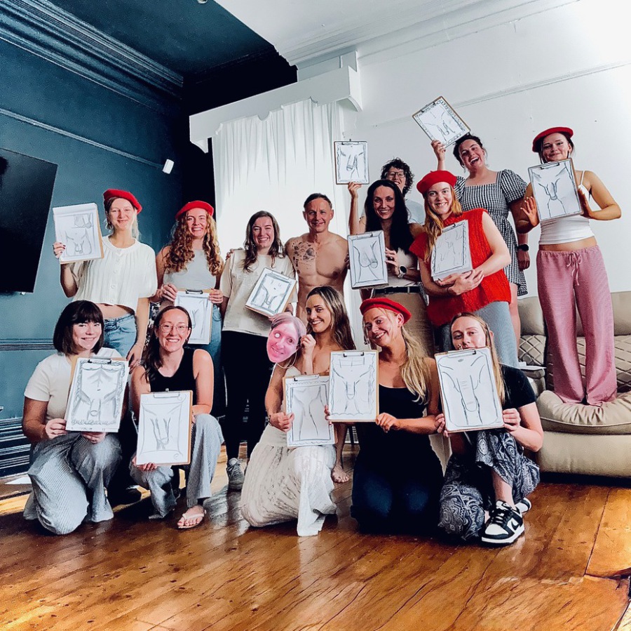 Small group of women at a hen party life drawing session proudly holding their nude art sketches, wearing fun berets.